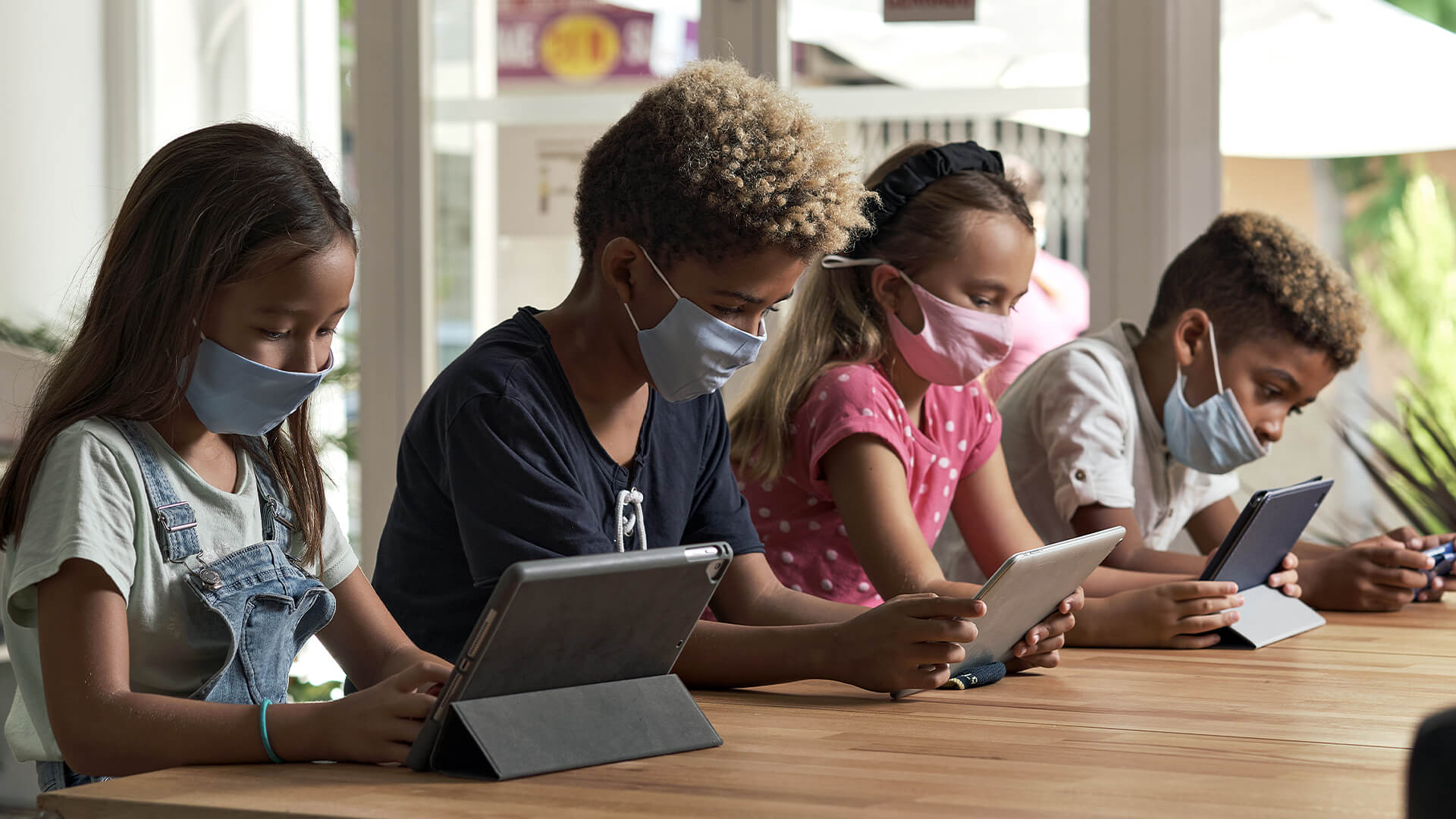 Students in masks using tablets