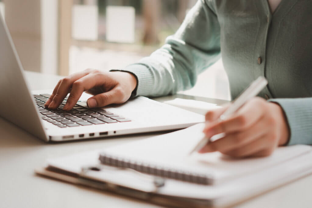 Business,Women,Work,On,Computers,And,Write,On,Notepad,With